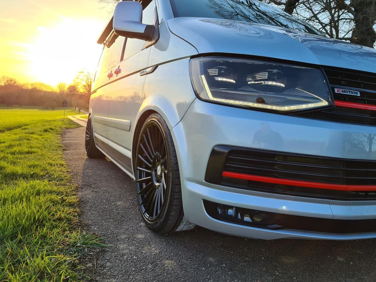 Silberner VW T6 4MOTION mit schwarzen Felgen im Abendlicht an einem Feldweg
